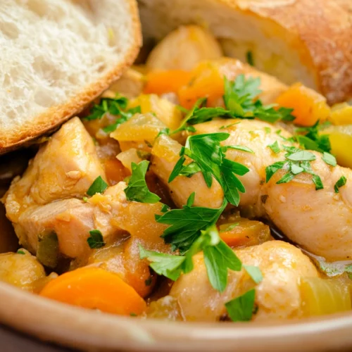 Bowl of chicken and vegetable stew garnished with fresh parsley